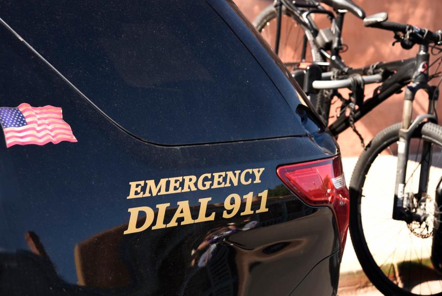 "Emergency Dial 911" sticker on the side of a black police patrol car