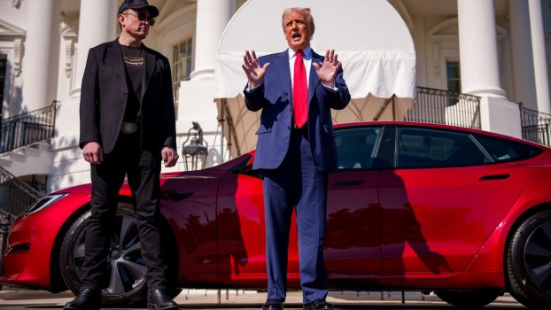 President Donald Trump and Elon Musk stand next to red Tesla outside the White House