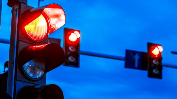Three red traffic lights against a dark blue night sky.