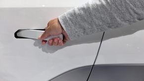 Driver opens the retractable door handle in a white EV