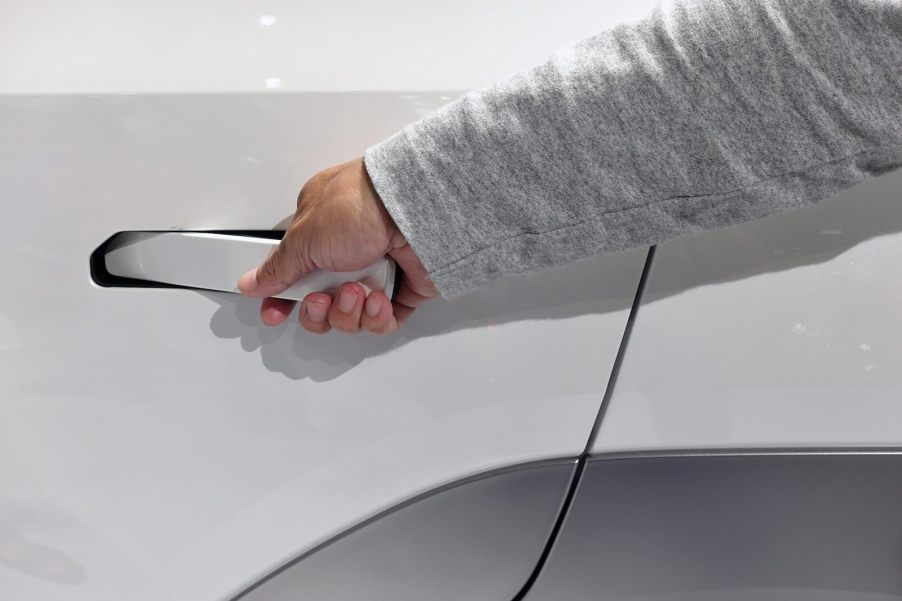Driver opens the retractable door handle in a white EV