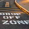 The "drop off zone" paint on the tarmac of a school parking lot.