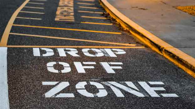 The "drop off zone" paint on the tarmac of a school parking lot.