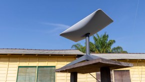Starlink antenna in front of a house, palm trees in the background.