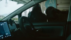 Two men in masks examine car for valuable before breaking in