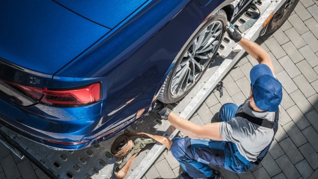 A toe truck operator loading a sedan
