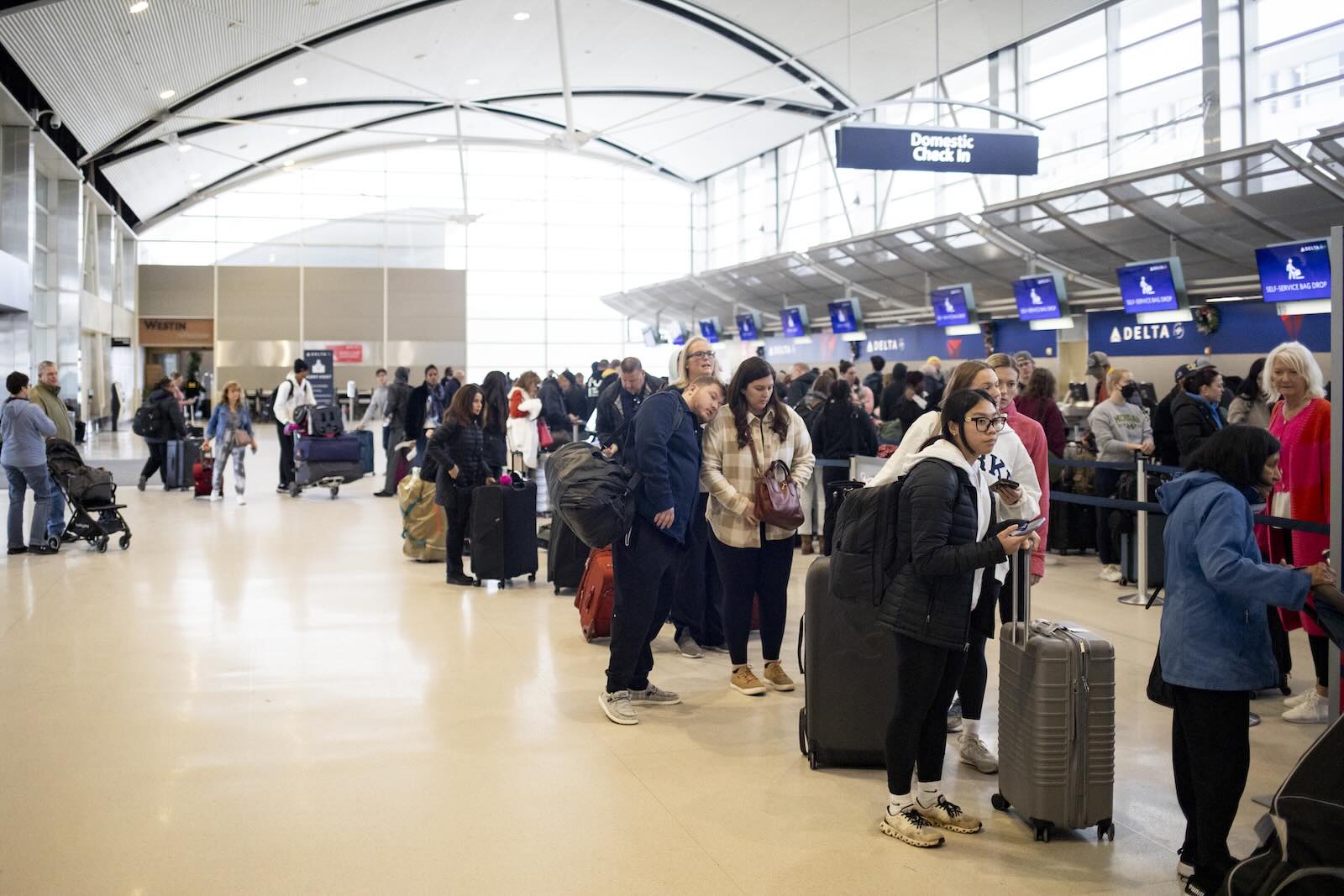 Row of travelers wait in line at the Detroit airport ticket counter.
