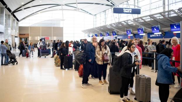Row of travelers wait in line at the Detroit airport ticket counter.