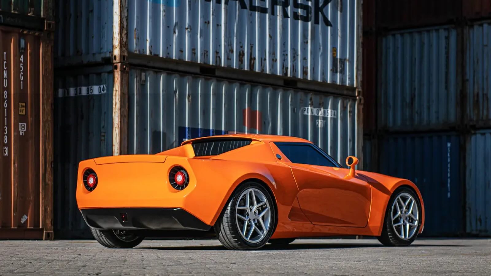 Bright orange electric "SC01" Chinese electric coupe parked in front of European shipping containers.