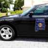 Black Dodge Charger patrol car with an Alabama State Trooper door badge parked by a park.
