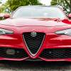 Front of a red Alfa Romeo Giulia sedan, a parking lot visible in the background.