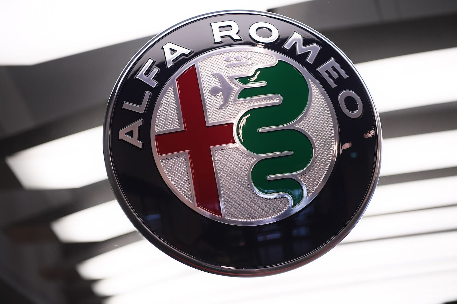 The Alfa Romeo logo badge on a blurry white background.