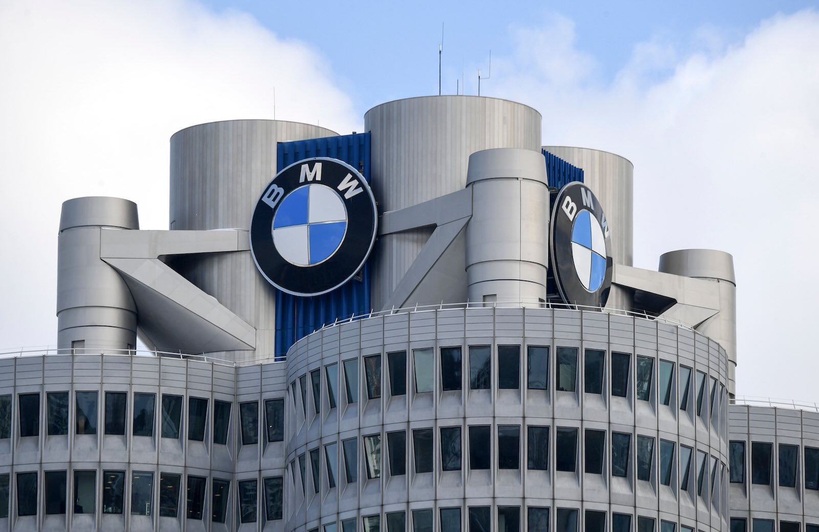 The BMW logo on top of an office building, blue sky in the background.