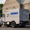Tan brinks armored truck parked in front of a tan building.