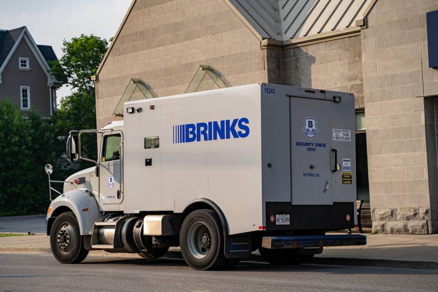 Tan brinks armored truck parked in front of a tan building.