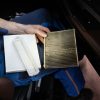 Technician holds an old and new cabin air filter in a car