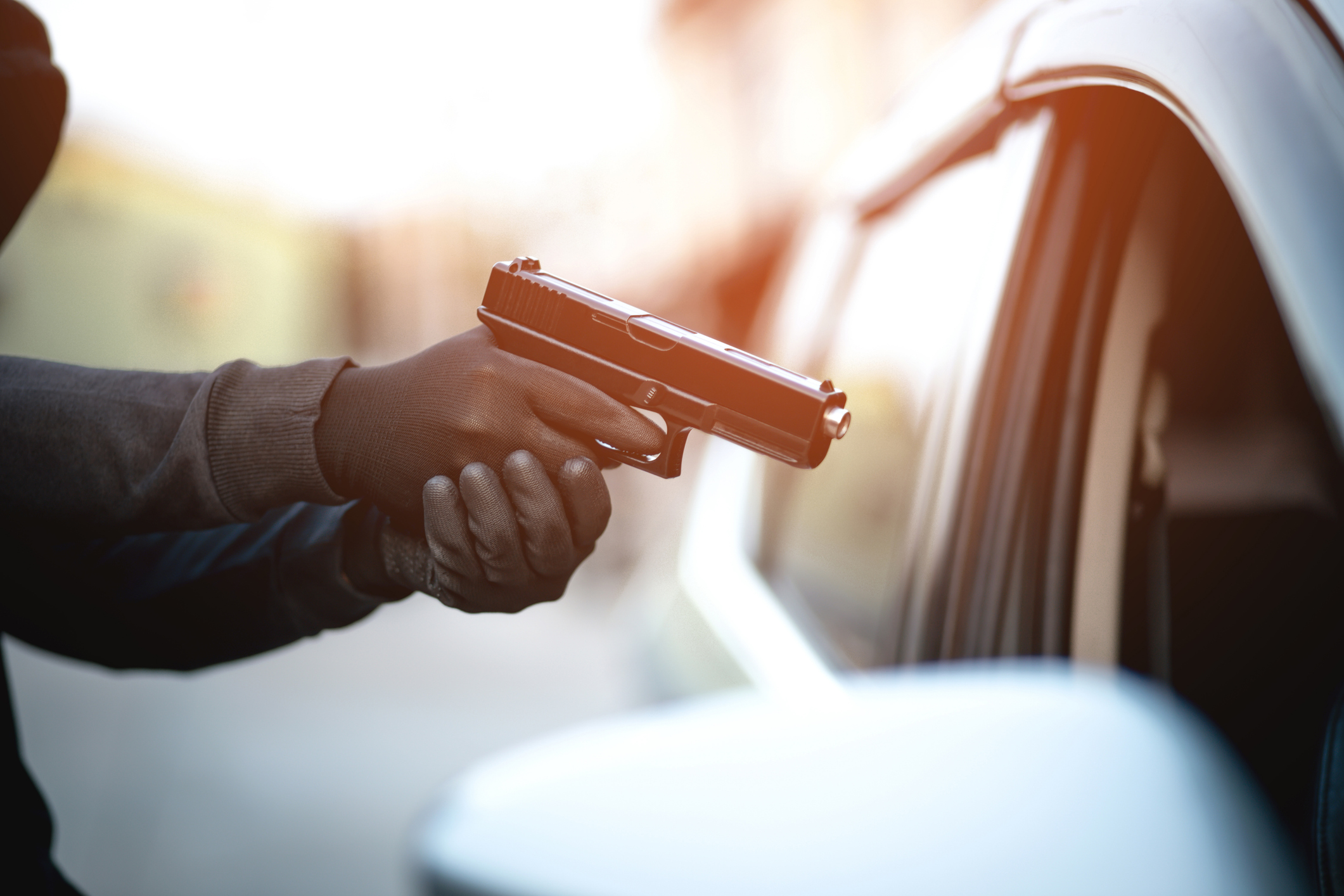 A man stealing a car with a gun