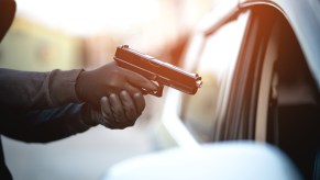 A man stealing a car with a gun