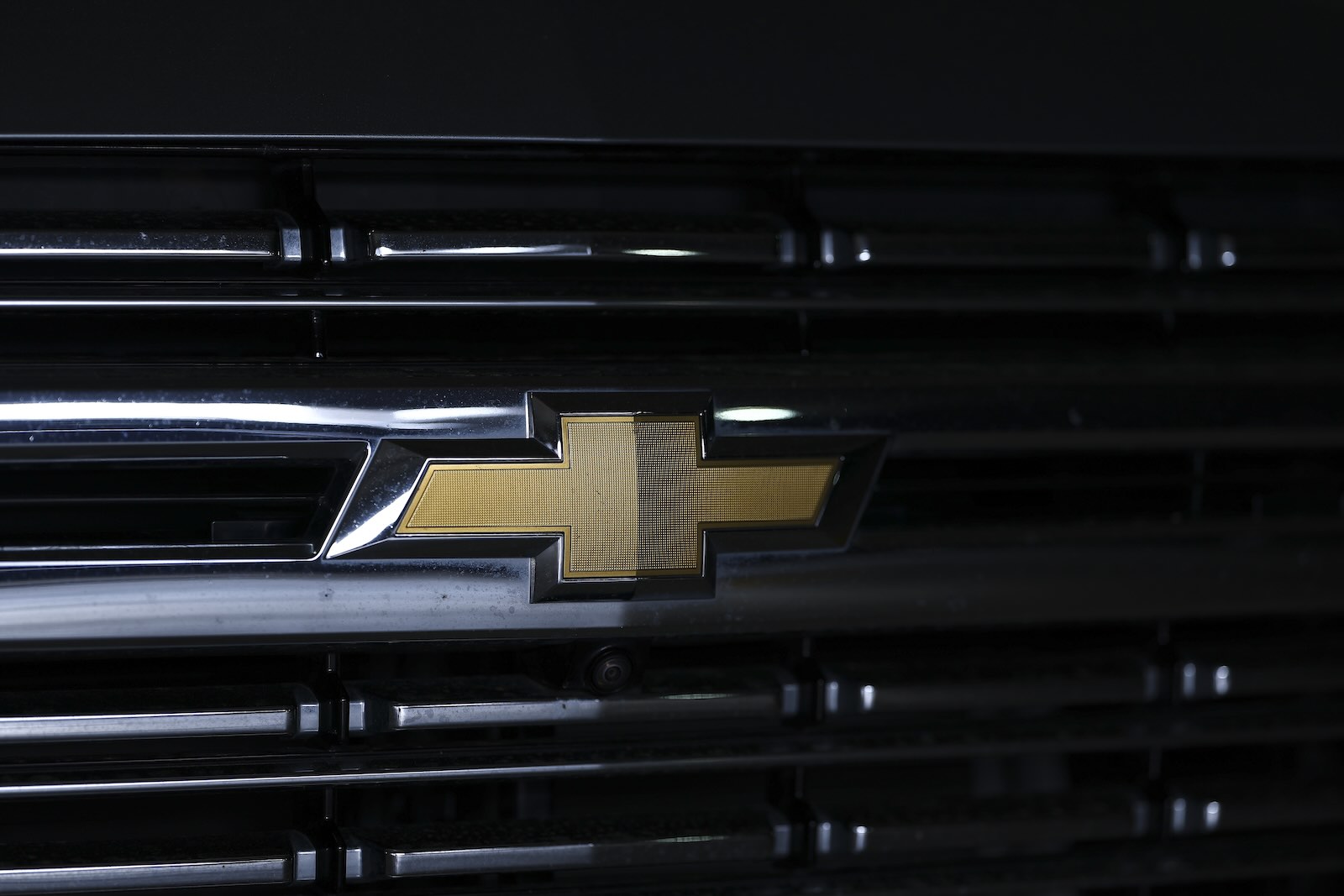 The gold bowtie logo on a black Silverado EV pickup truck grill.