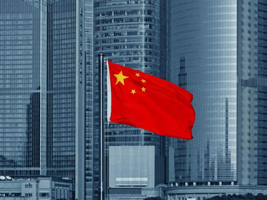 Red Chinese flag in front of skyscrapers.