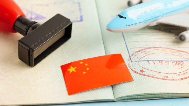 Embassy employee's Chinese stamp on a passport, model airplane in the background.