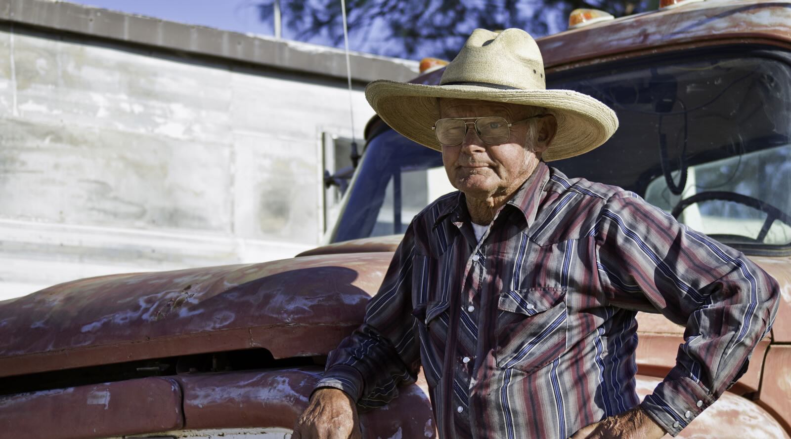 Older pickup truck driver leans against his Silverado hood.