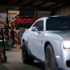 Silver Dodge Challenger Hellcat Demon muscle car in garage.