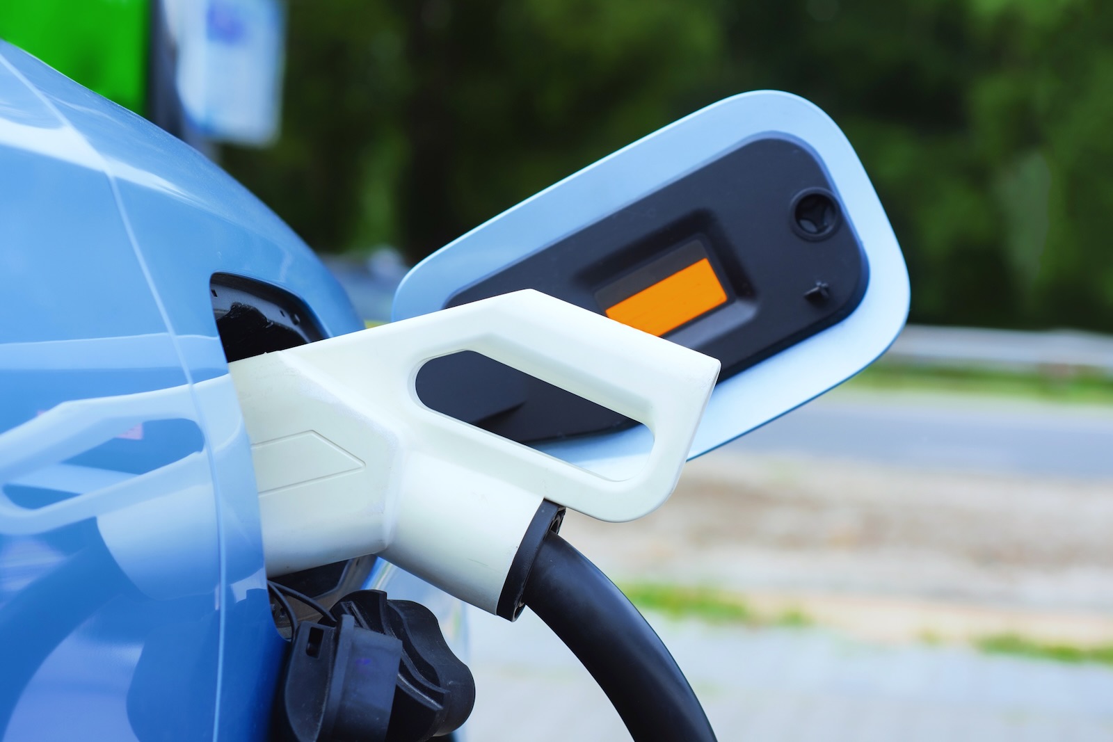 Blue electric vehicle hooked up to a charging cable.