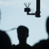 The silhouettes of a crowd of people approach a surveillance camera.