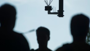 The silhouettes of a crowd of people approach a surveillance camera.