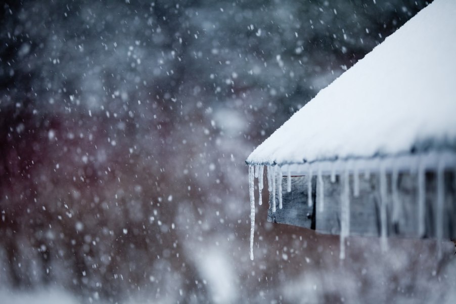 Icicles hanging from a roof during a snow storm.