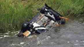 Flipped Jeep in a Florida canal, a grassy field in the background.
