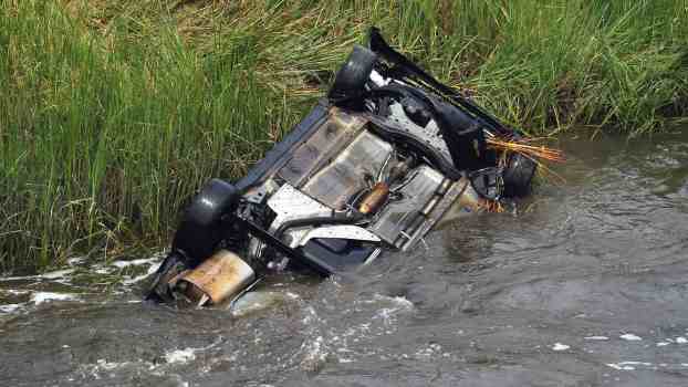 Flipped Jeep in a Florida canal, a grassy field in the background.