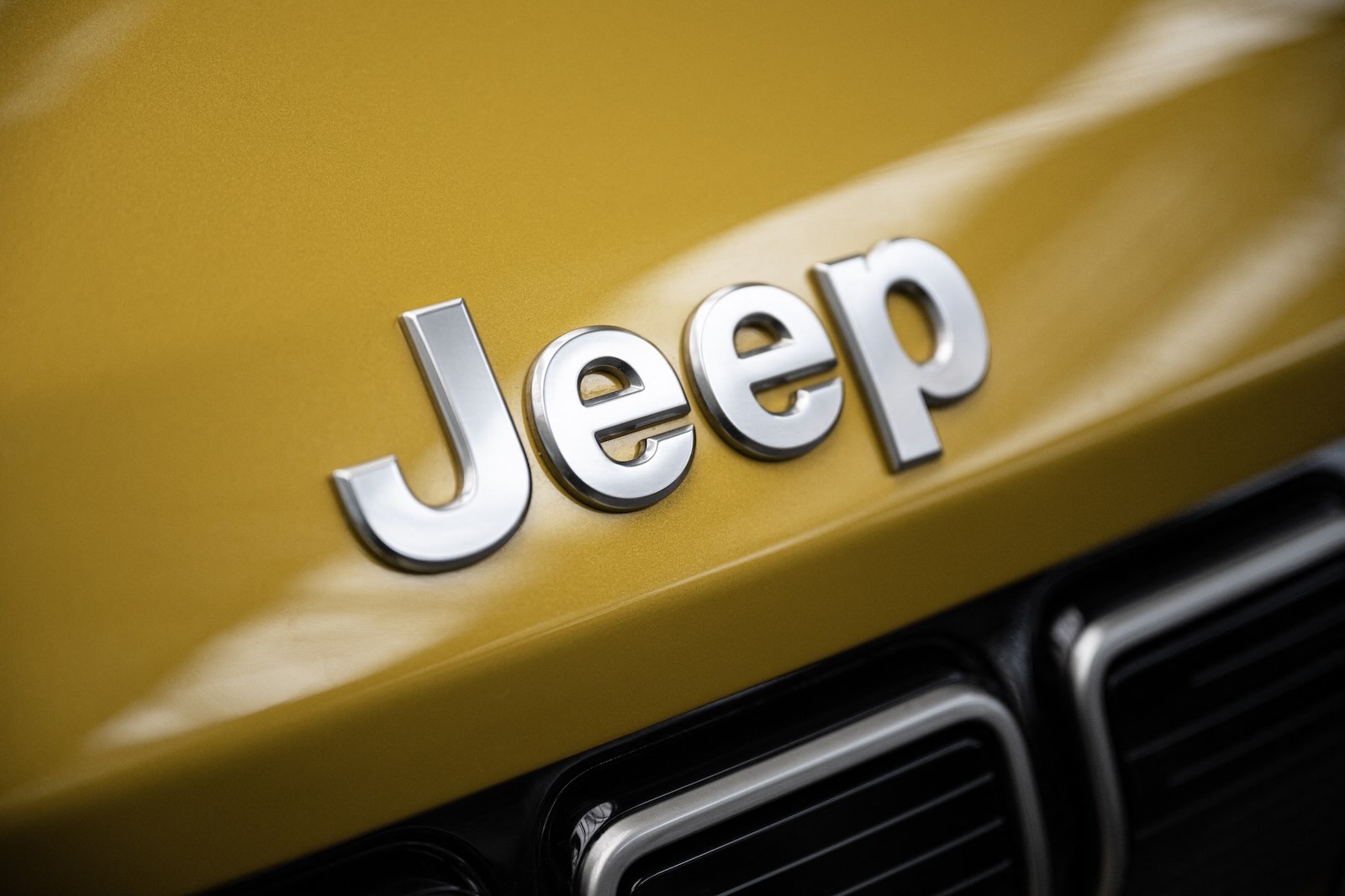 Chrome Jeep logo on the gold hood of an SUV.
