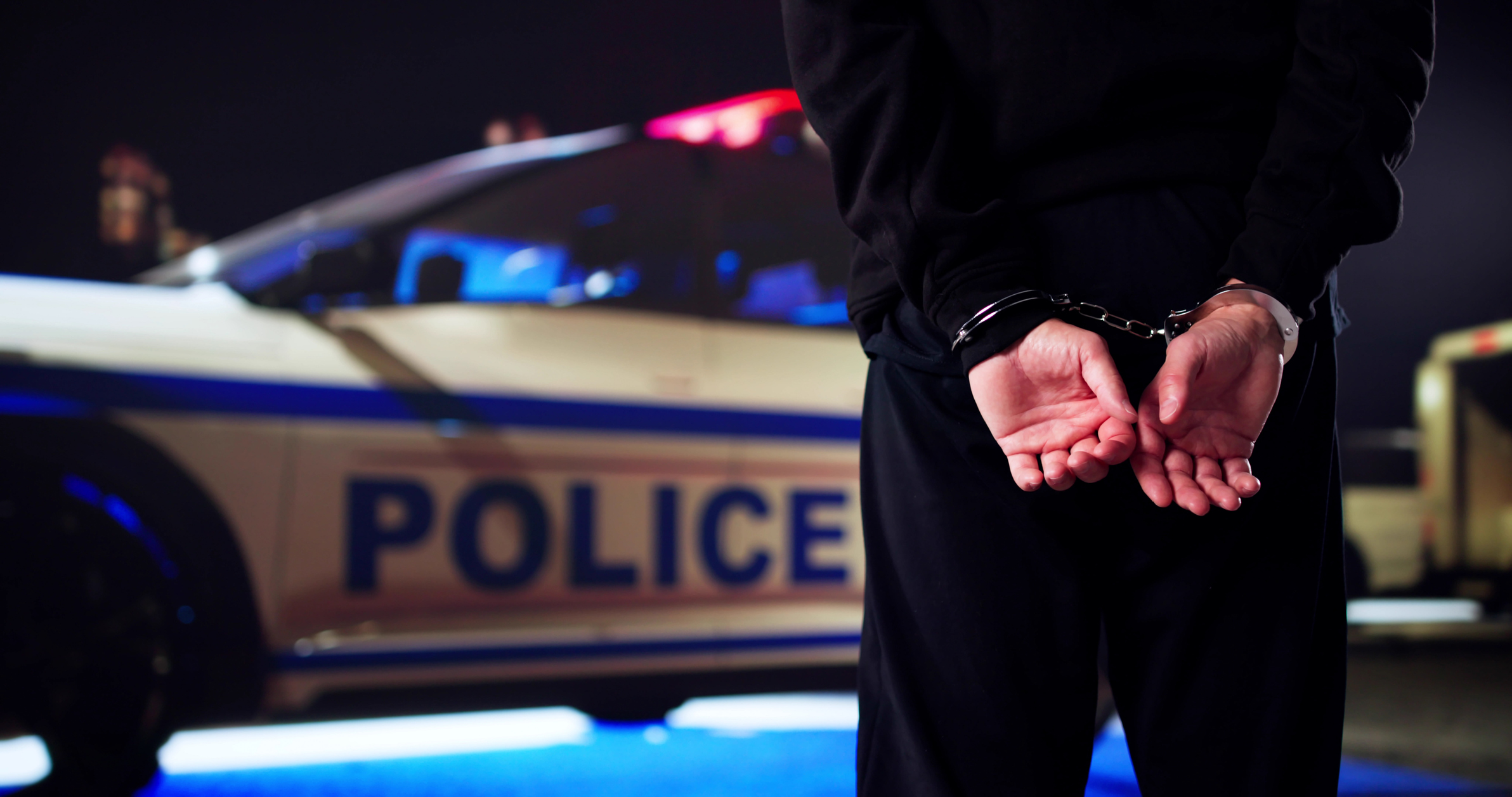 A man being arrested by a police car