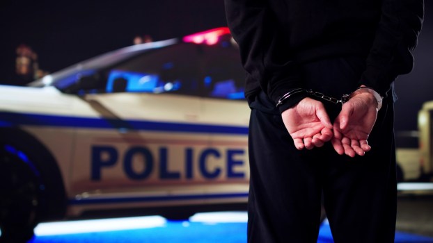 A man being arrested by a police car