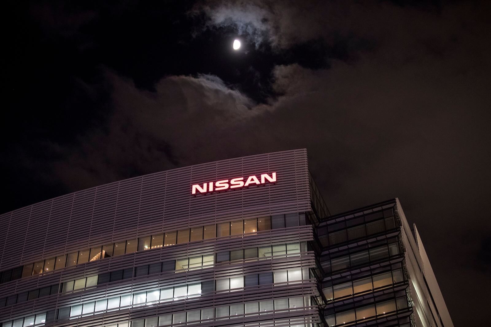 The Nissan sign above the headquarters office building in Japan, a full moon in the background.