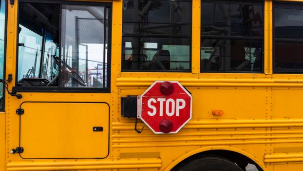 Red sign on a yellow school bus at a Florida stop.