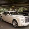 White Rolls Royce with a valet parking attendant walking behind it.