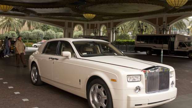 White Rolls Royce with a valet parking attendant walking behind it.