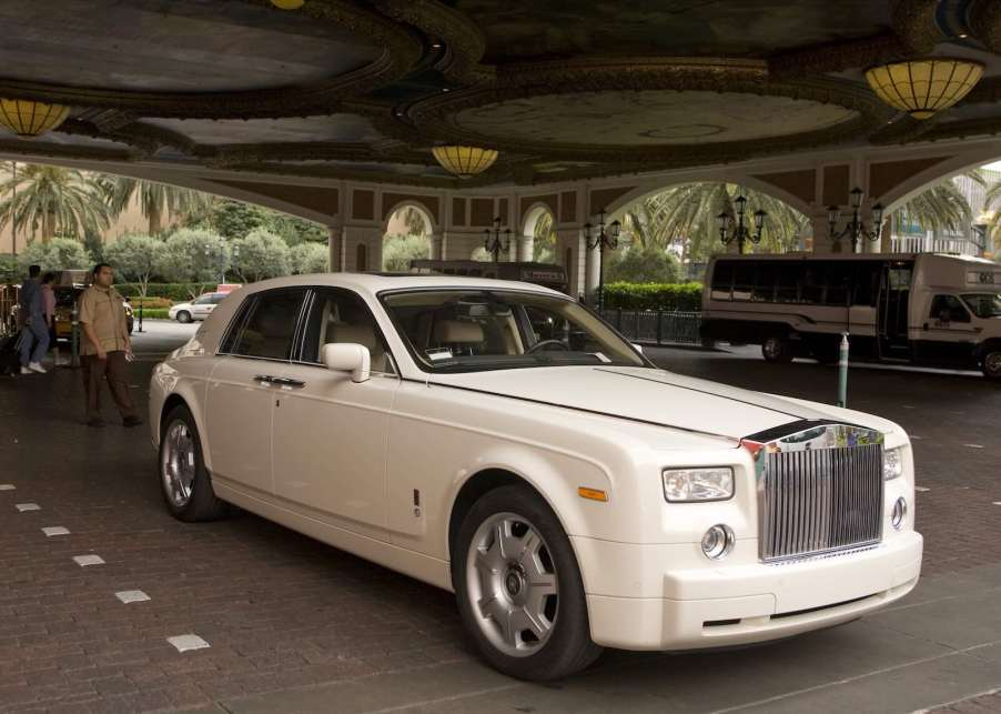 White Rolls Royce with a valet parking attendant walking behind it.