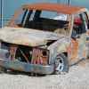 Scrapped and burned half-ton truck sits in a junkyard.