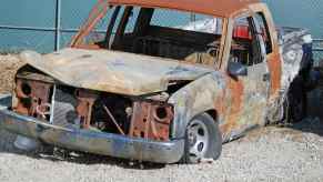 Scrapped and burned half-ton truck sits in a junkyard.