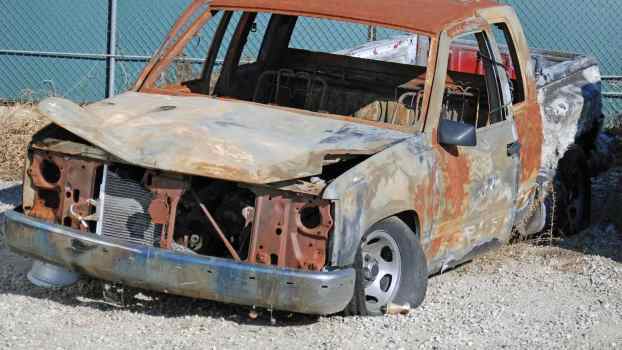 Scrapped and burned half-ton truck sits in a junkyard.