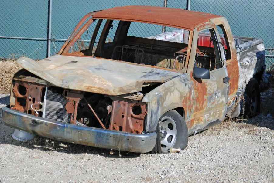 Scrapped and burned half-ton truck sits in a junkyard.
