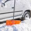 Orange shovel in front of white SUV covered in snow.