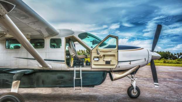 Plane with open door parked on the runway.