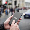 Man holding a smartphone starts the Uber app, a street full of cars visible in the background.
