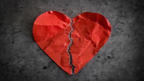 Torn red Valentine's Day heart on a concrete background.