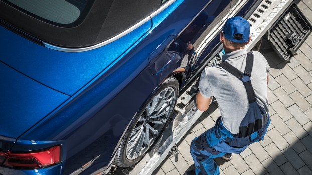 A tow truck operator loading a car
